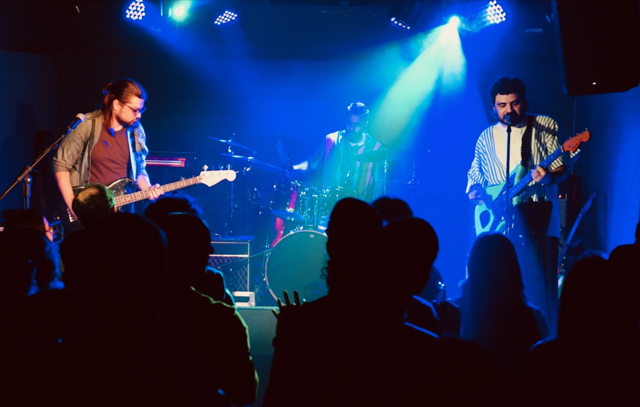 Fresta se apresentando ao vivo diante do público, sob luzes azuis